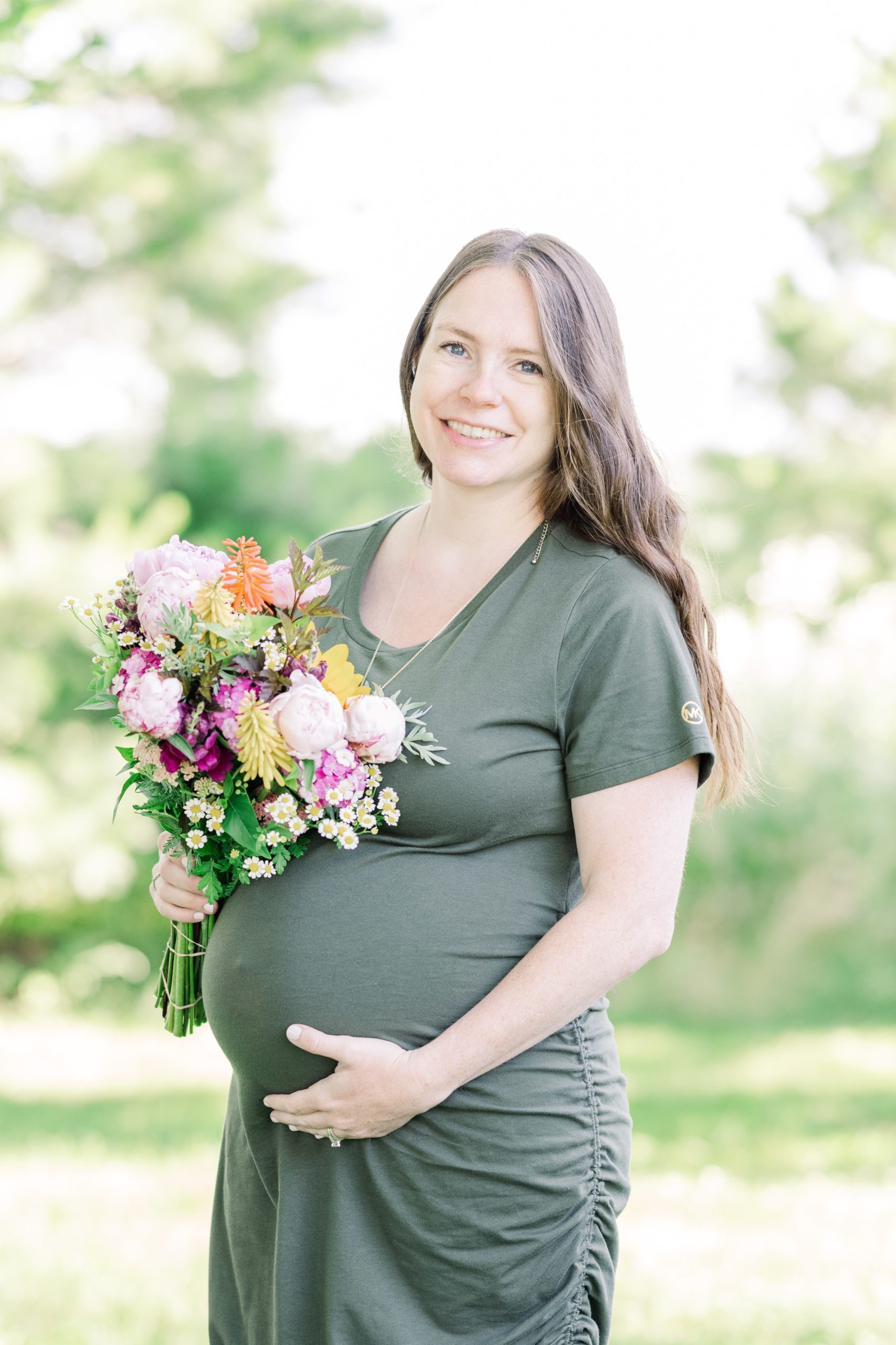 Mom holding baby bump and fresh flowers
