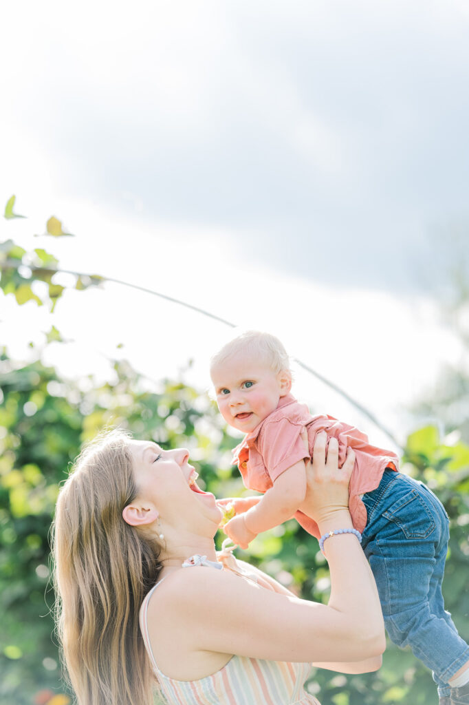 mom picking up toddler for giggles and smiles in pretty bird farm Stockton NJ Golden Heart Photography Anne Haug Hunterdon County NJ Family Photographer