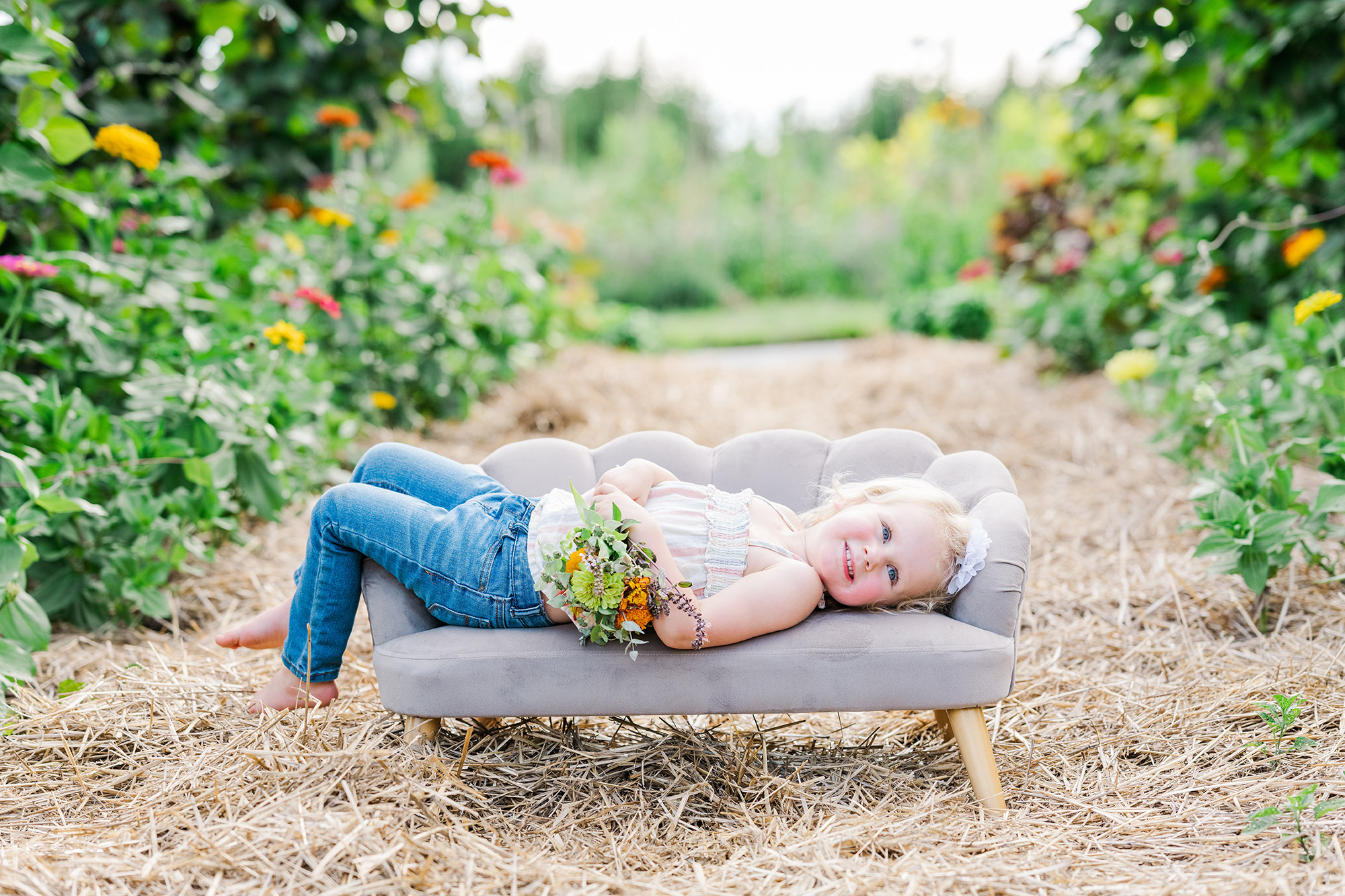 toddler poses on mini couch in flower tunnel with Golden Heart Photography by Anne Haug Flemington NJ Photographer