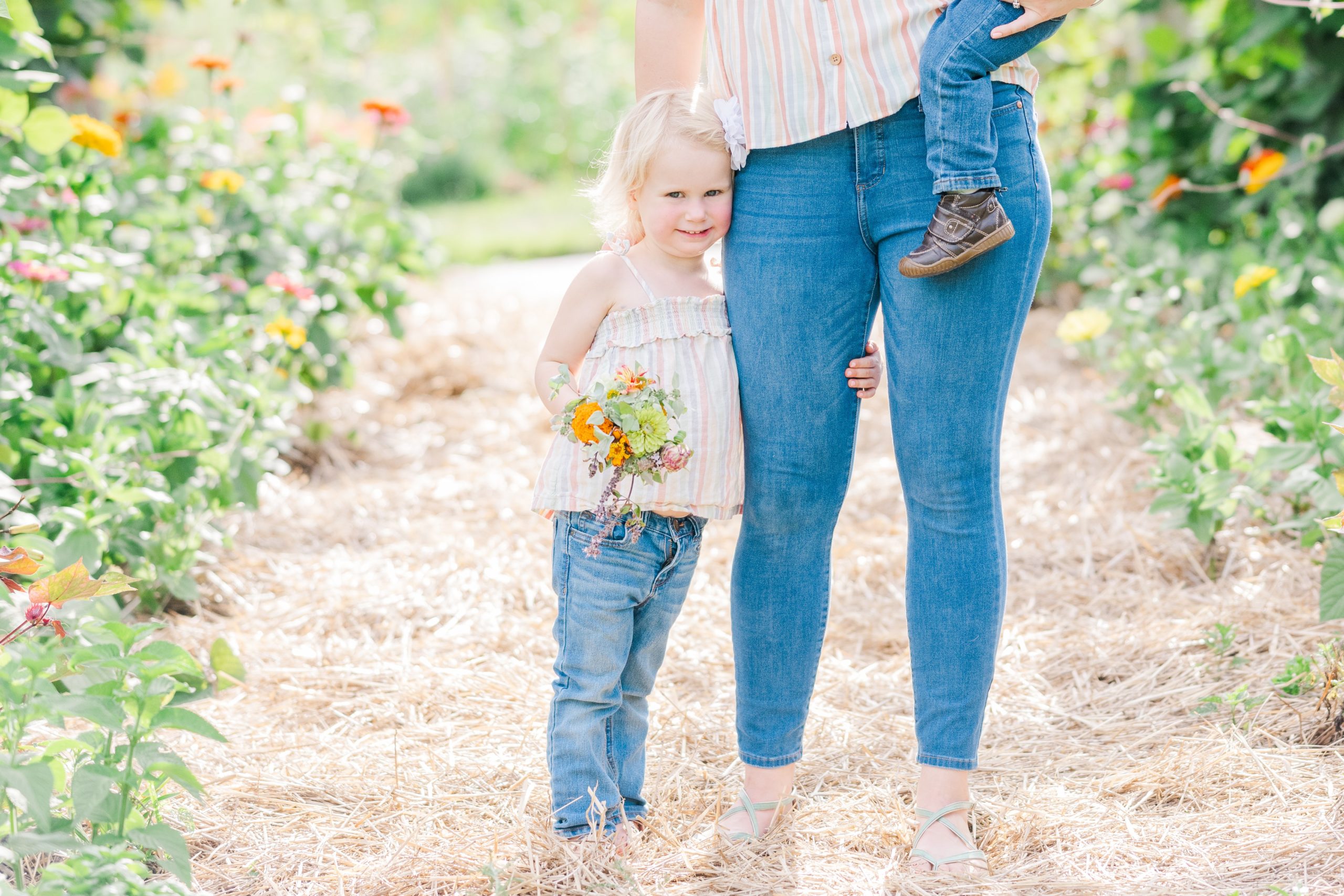 toddler hugs moms leg at flower garden mini session mommy & me Pretty Bird Farms Stockton NJ