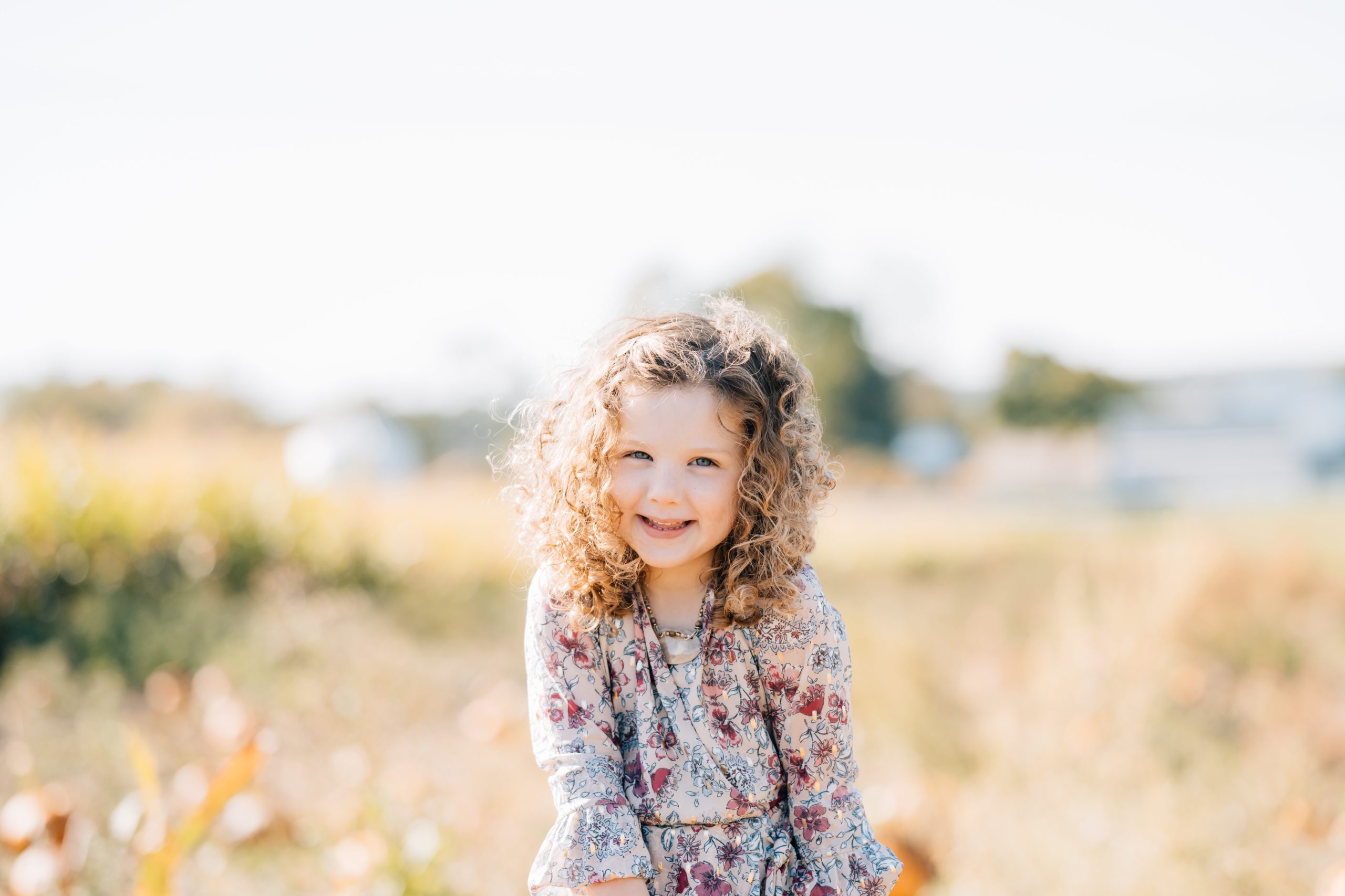 daughter poses individually in beautiful flower pattern fall dressduring at Pumpkin Junction at Everitt Farms in Flemington, NJ Ringoes, NJ with Motherhood and Family Photographer Anne Haug of Golden Heart Photography.