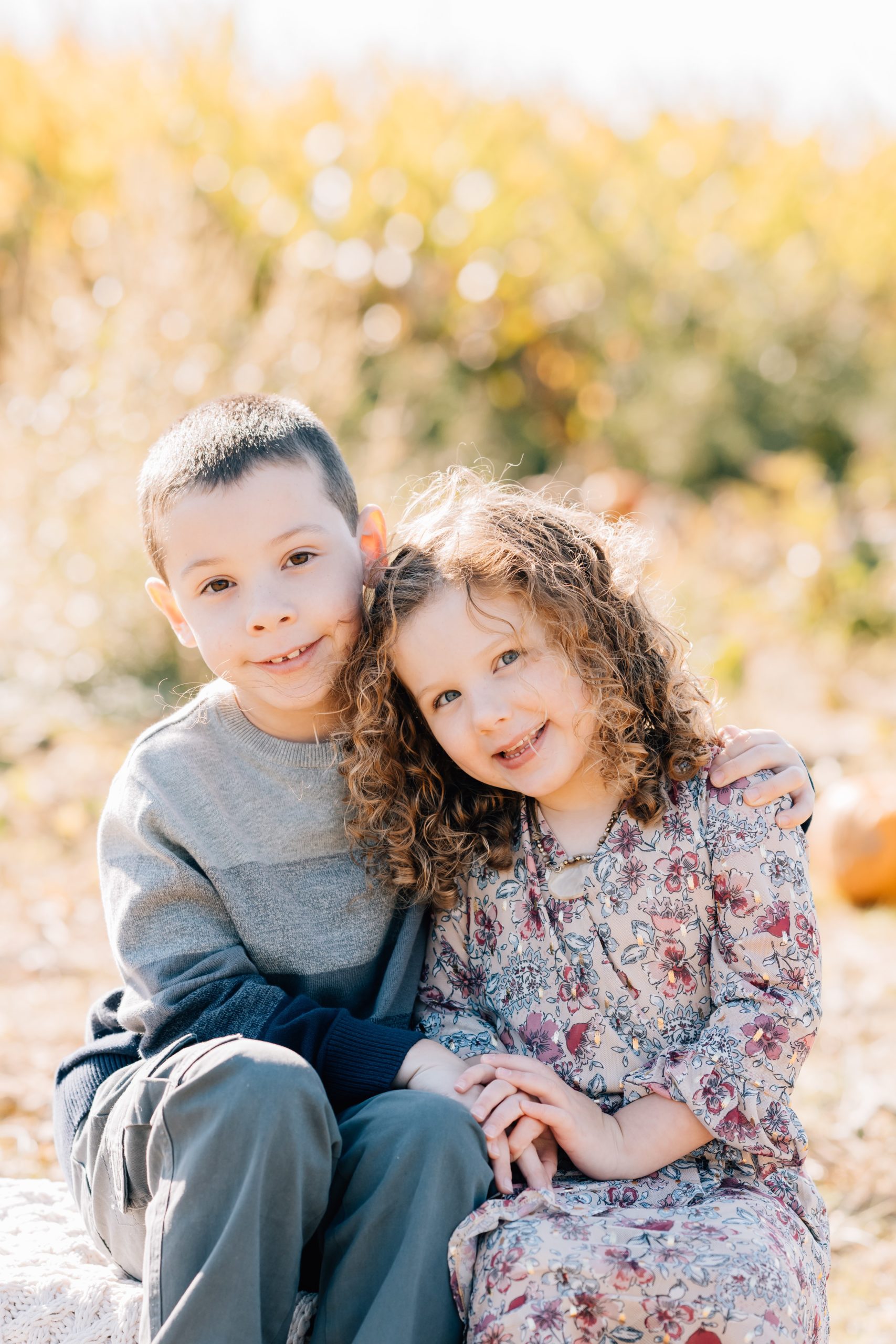 brother and sister pose in pumpkin patch on barrel during fall mini portrait session at Pumpkin Junction at Everitt Farms in Flemington, NJ Ringoes, NJ with Motherhood and Family Photographer Anne Haug of Golden Heart Photography.