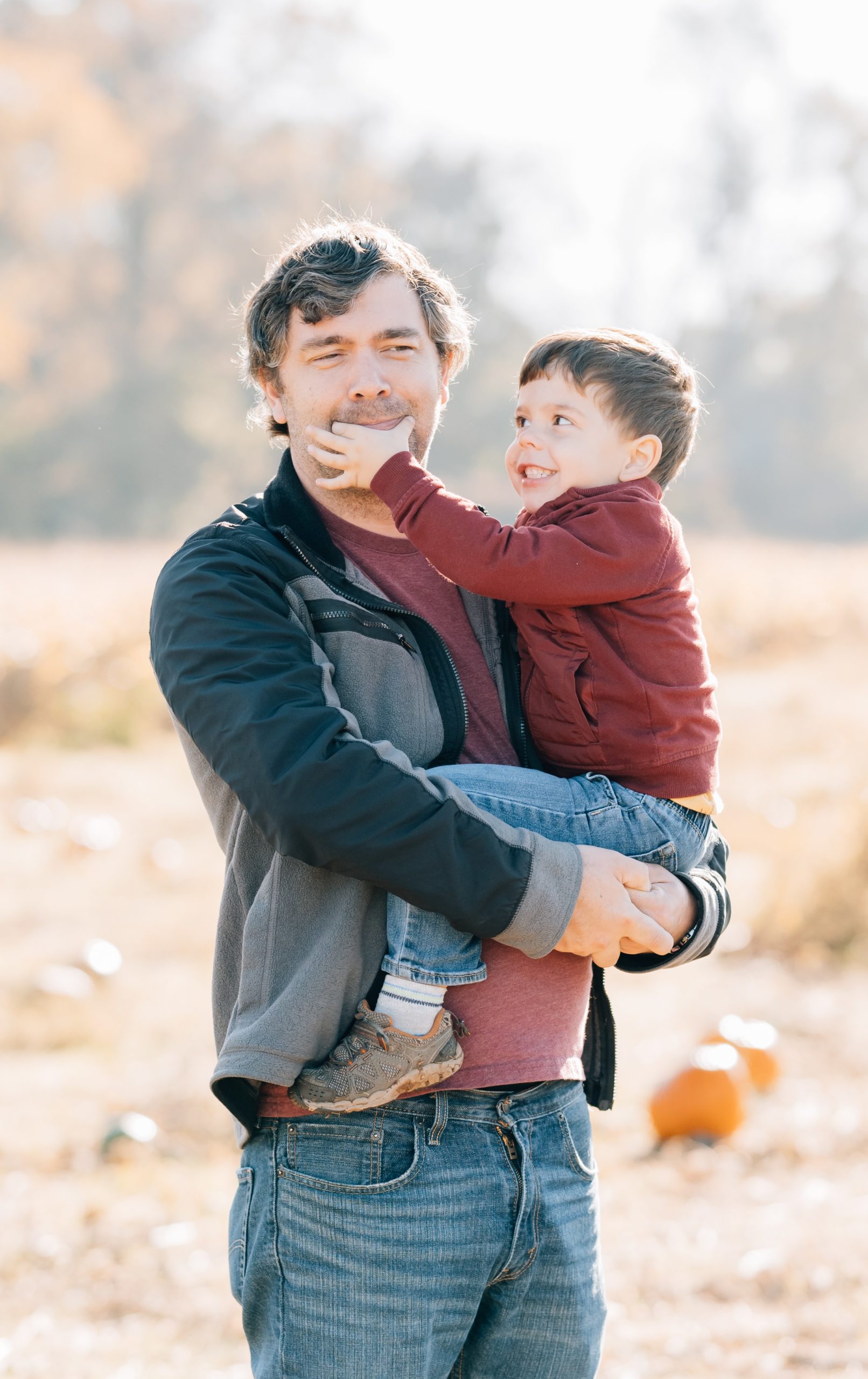 toddler poses with dad to smile for the camera at fall family session with Golden Heart Photography