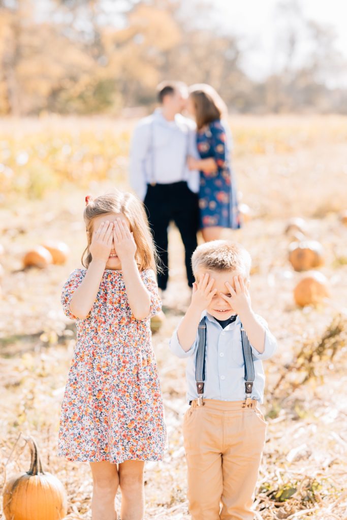 brother and sister cover eyes as mom and dad kiss  Flemington Fall Mini Session | NJ Photography | The Demetriou Family