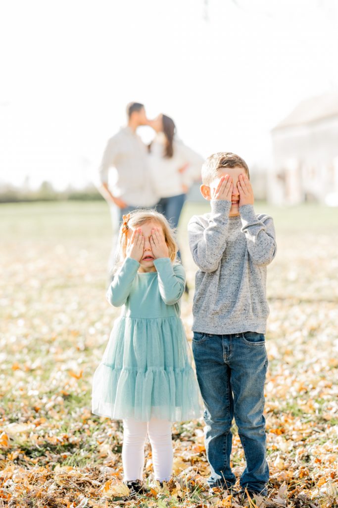kids cover eyes as mom and dad kiss at session with Golden Heart Photography