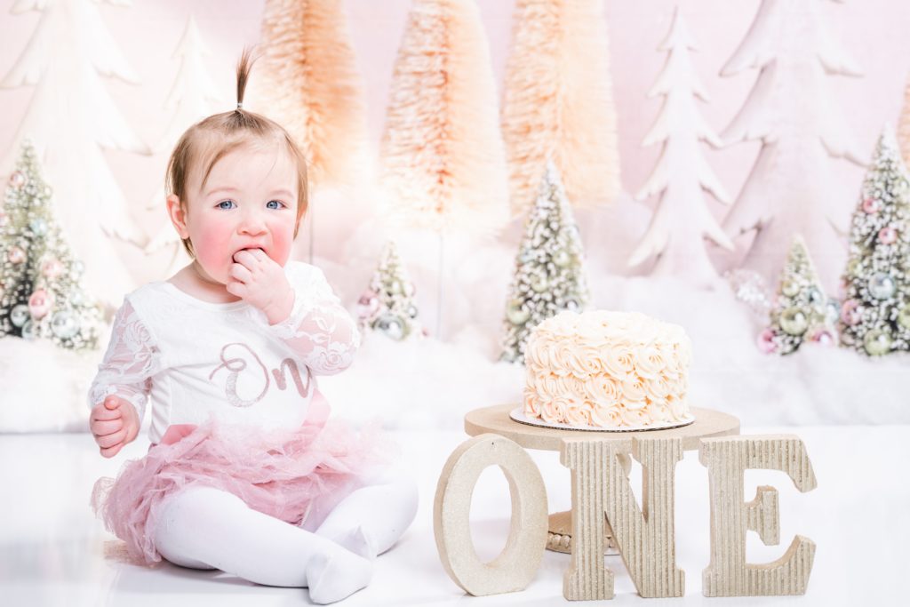 toddler girl eats cake at winter themed cake smash session with Golden Heart Photography
