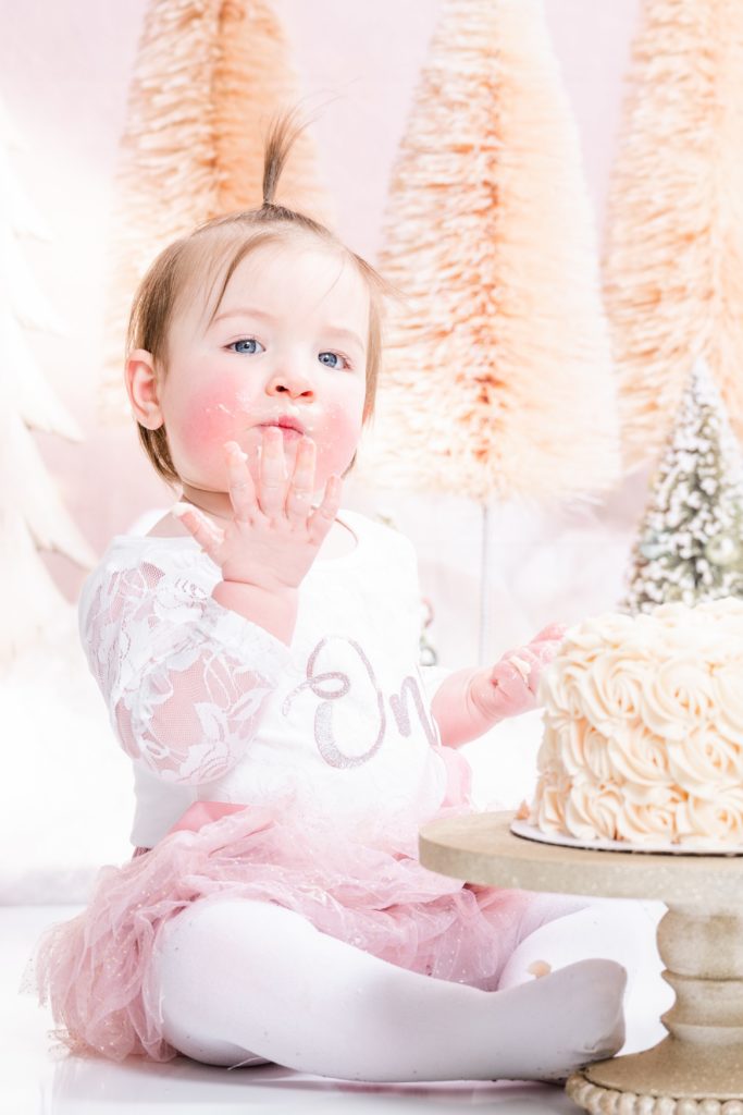 blowing cake kisses at cake smash session with Golden Heart Photography