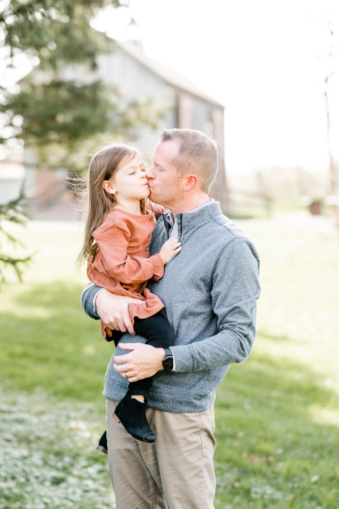 dad gives toddler daughter kiss on cheek at Golden Heart Photography family session