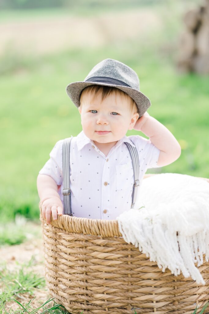 toddler boy sits in basket for portraits with Golden Heart Photography