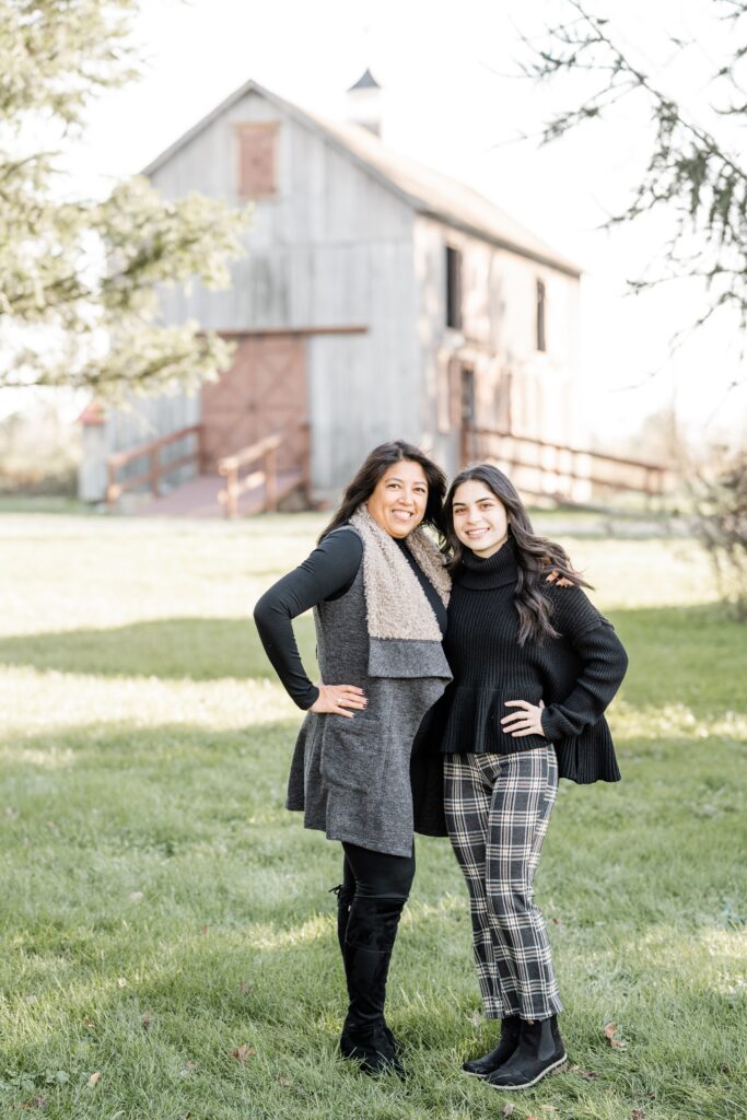 mother and daughter pose standing with rustic barn background with Golden Heart Photography