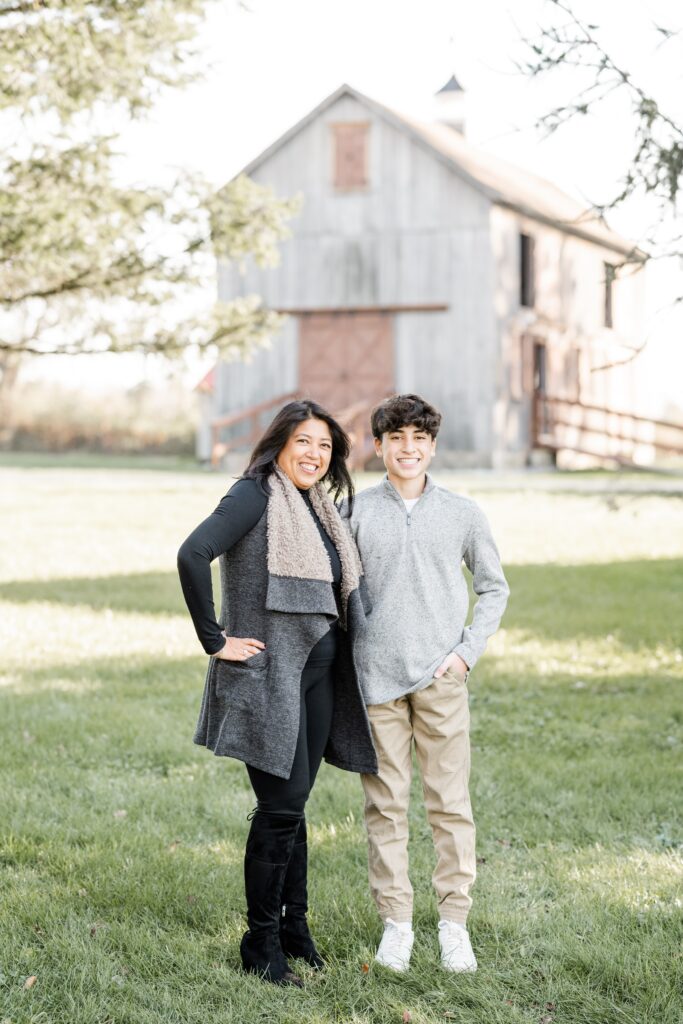 mom and son pose at session with Golden Heart Photography with beautiful rustic barn in background
