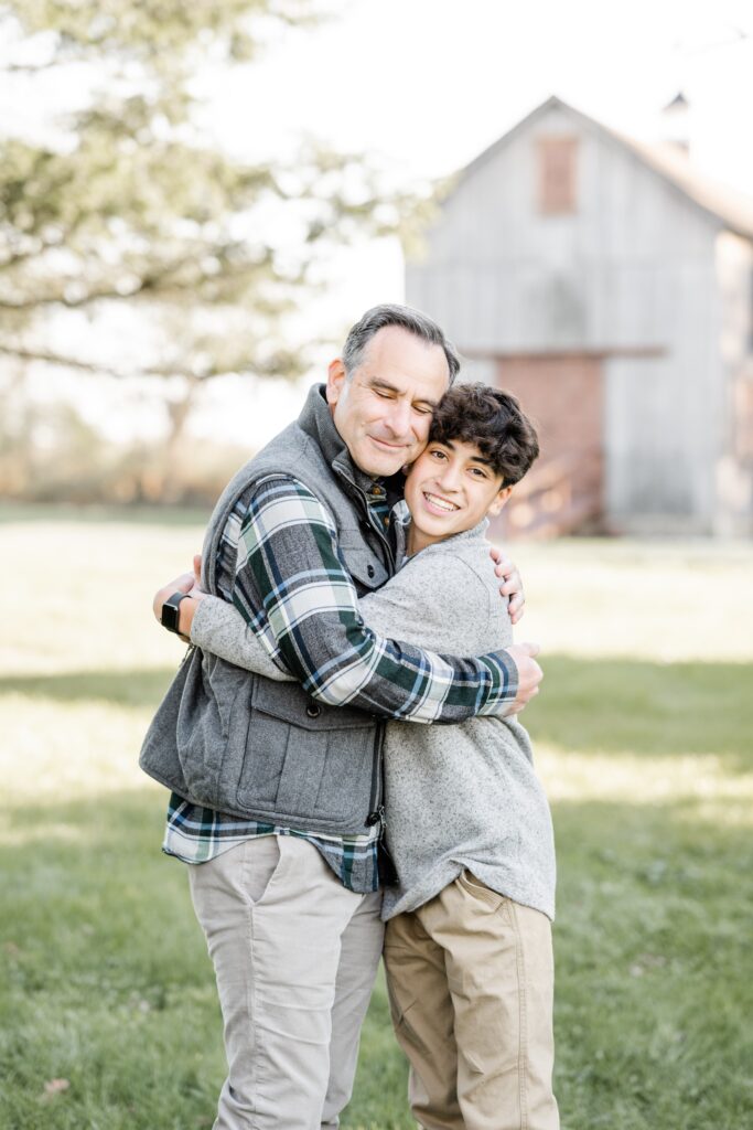 dad hugs son with barn in background with Golden Heart Photography