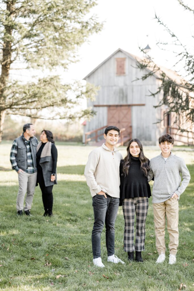 kids pose in foreground with parents and rustic farmstead in background with Golden Heart Photography