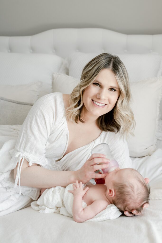 mom poses with baby at lifestyle in home newborn session with Golden Heart Photography